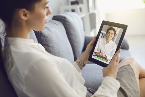 woman using tablet computer to talk to her doctor - telehealth